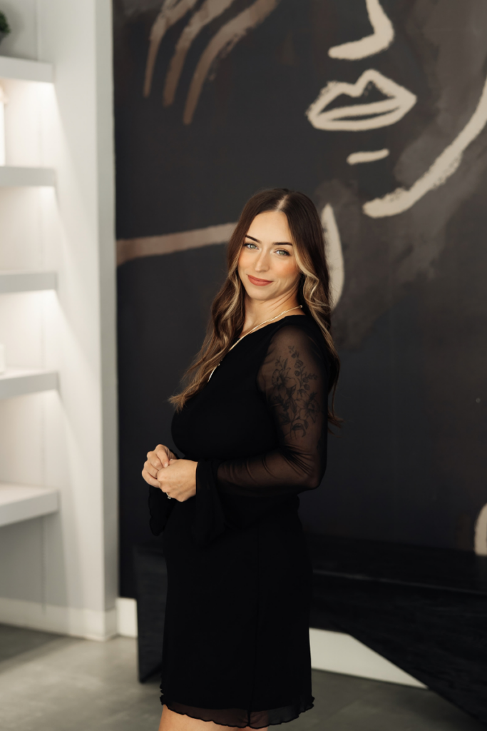 Portrait of esthetician Kayla Moore standing in front of a graphic wall mural.